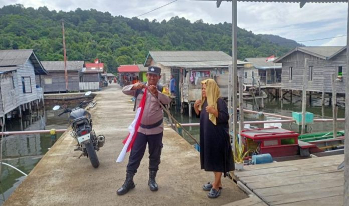 Bhabinkamtibmas Desa Kuala Maras Bagikan Bendera Merah Putih