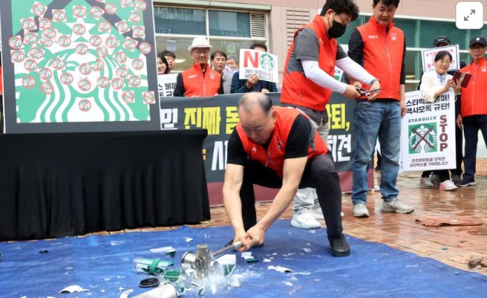 Seorang aktivis menghancurkan gelas dan cangkir Starbucks selama protes terhadap kampanye Tank Day Starbucks